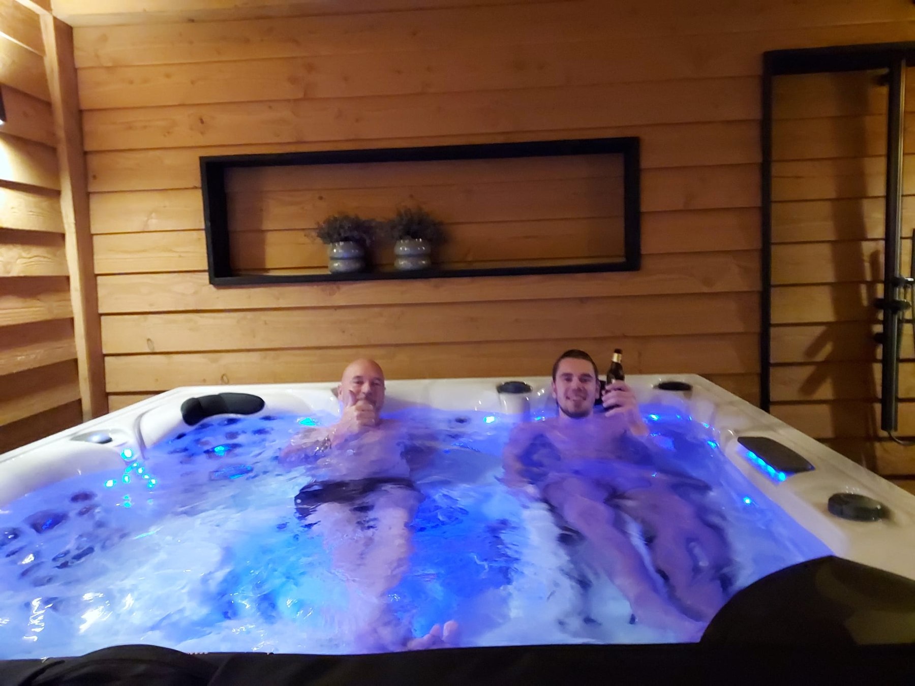 Spa in gebruik met blauwe verlichting in de houten wellnessruimte in Elburg.