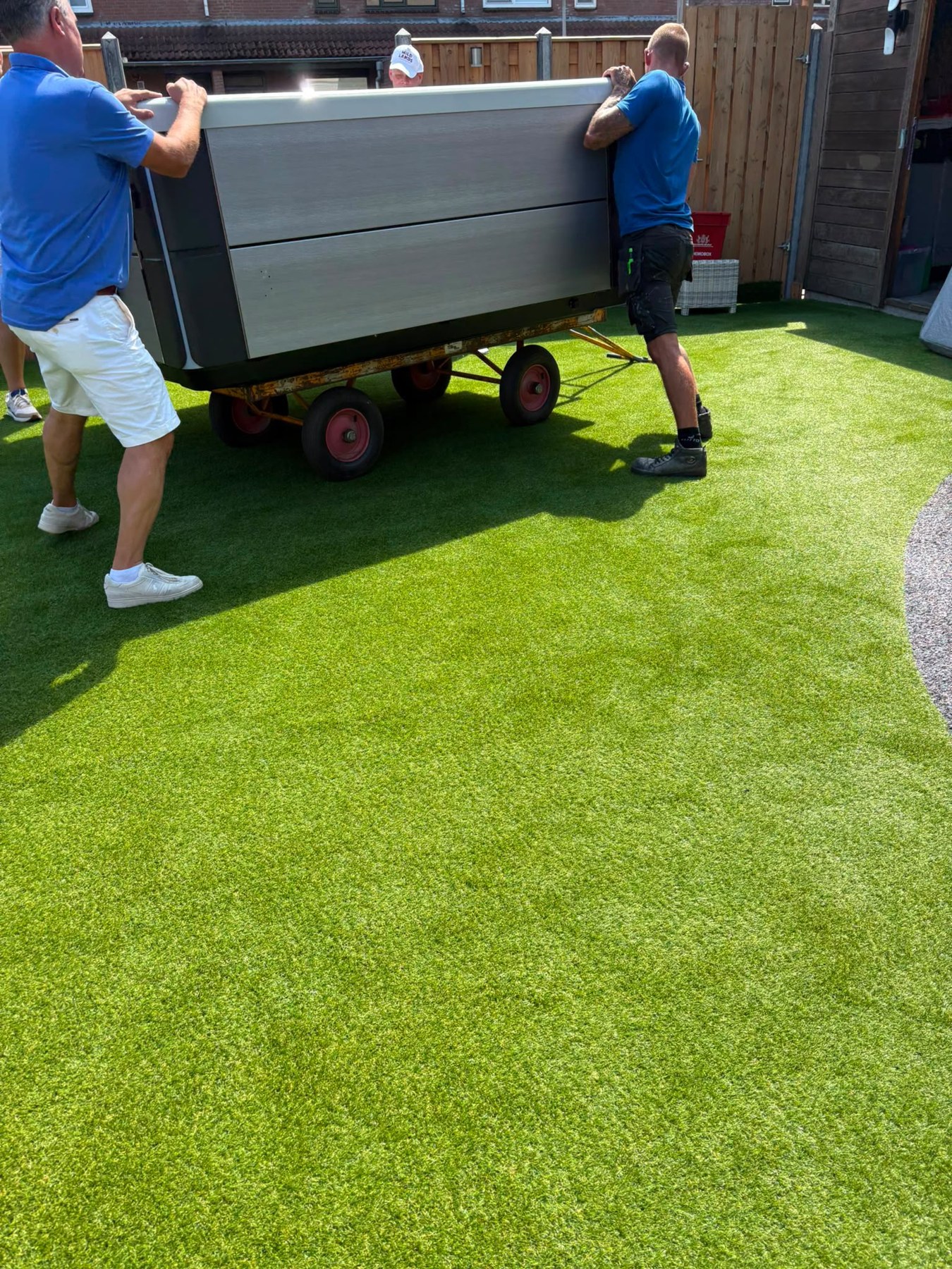 Werkzaamheden op locatie in Lelystad: transport van een spa door de tuin.