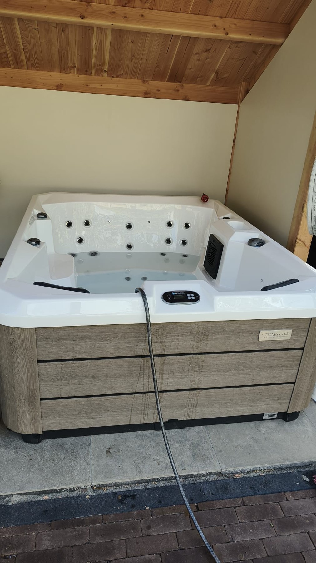 Spa met witte binnenzijde en houtlook buitenbekleding onder de overkapping in Oldebroek.