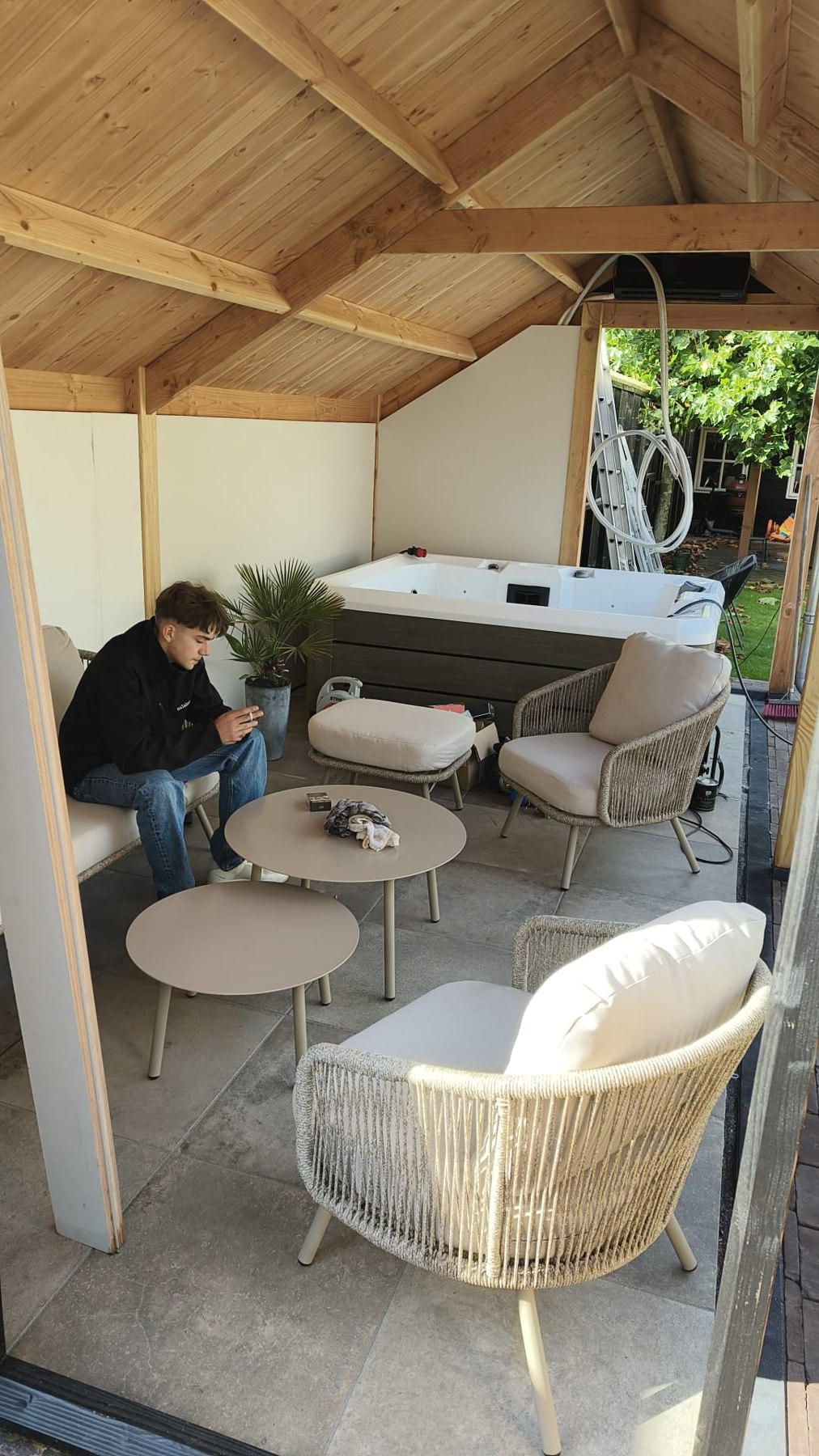 Overzicht van de houten overkapping met spa en tuinmeubels in Oldebroek.