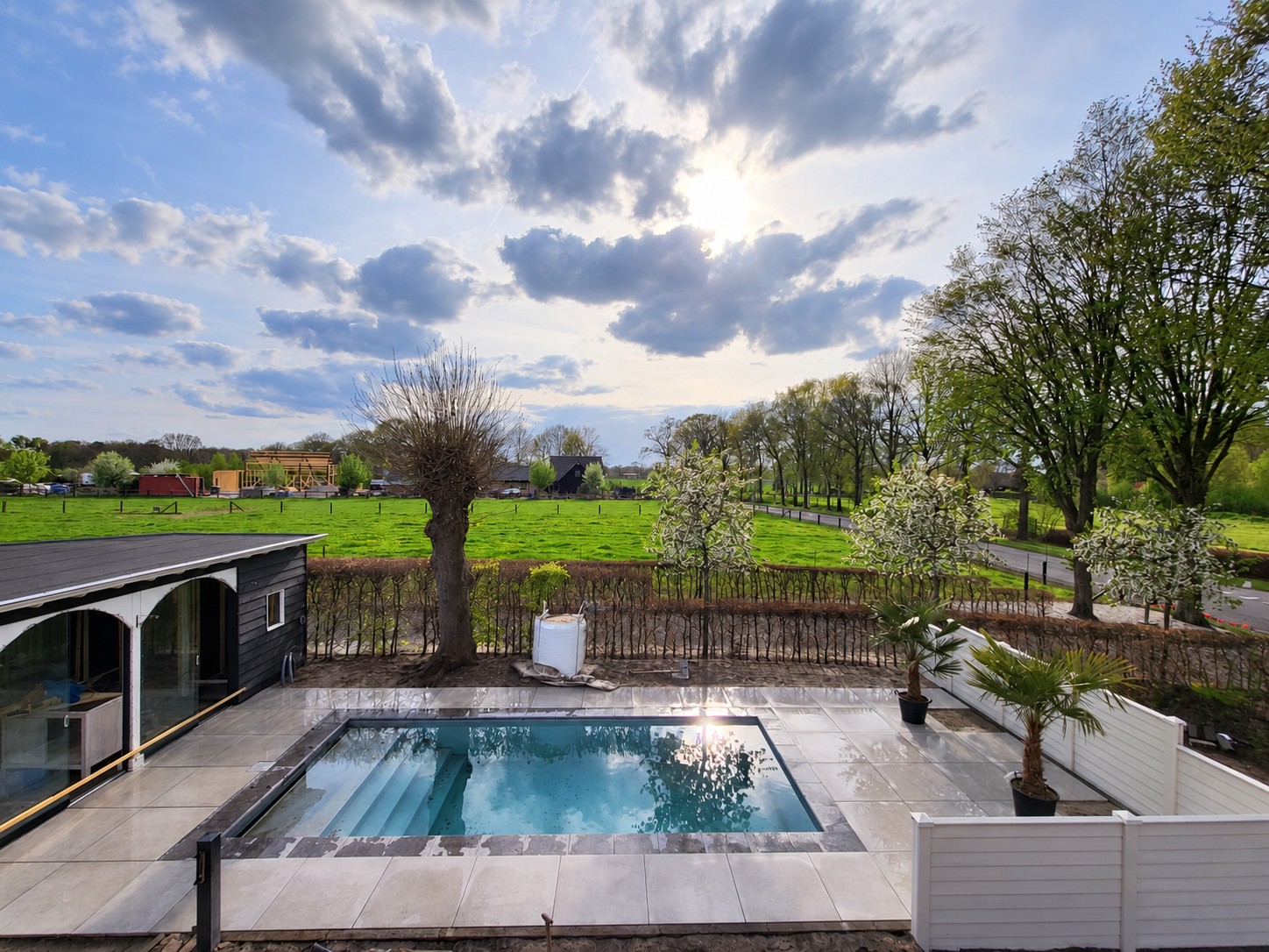 Overzicht van het zwembad, terras en landelijke omgeving in Doornspijk.