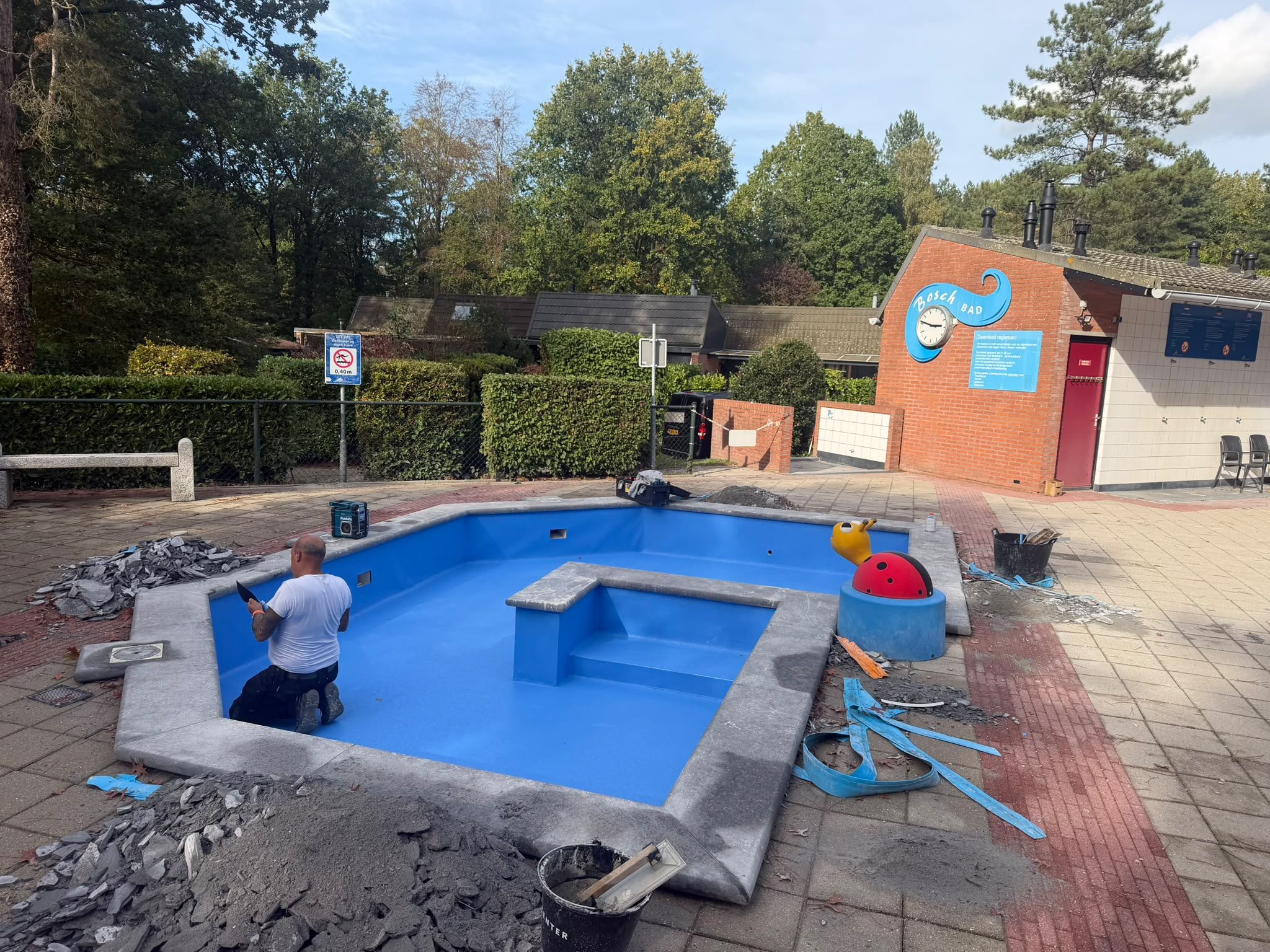 Kleiner buitenbad met een medewerker tijdens werkzaamheden aan het zwembadcomplex. · foto 2