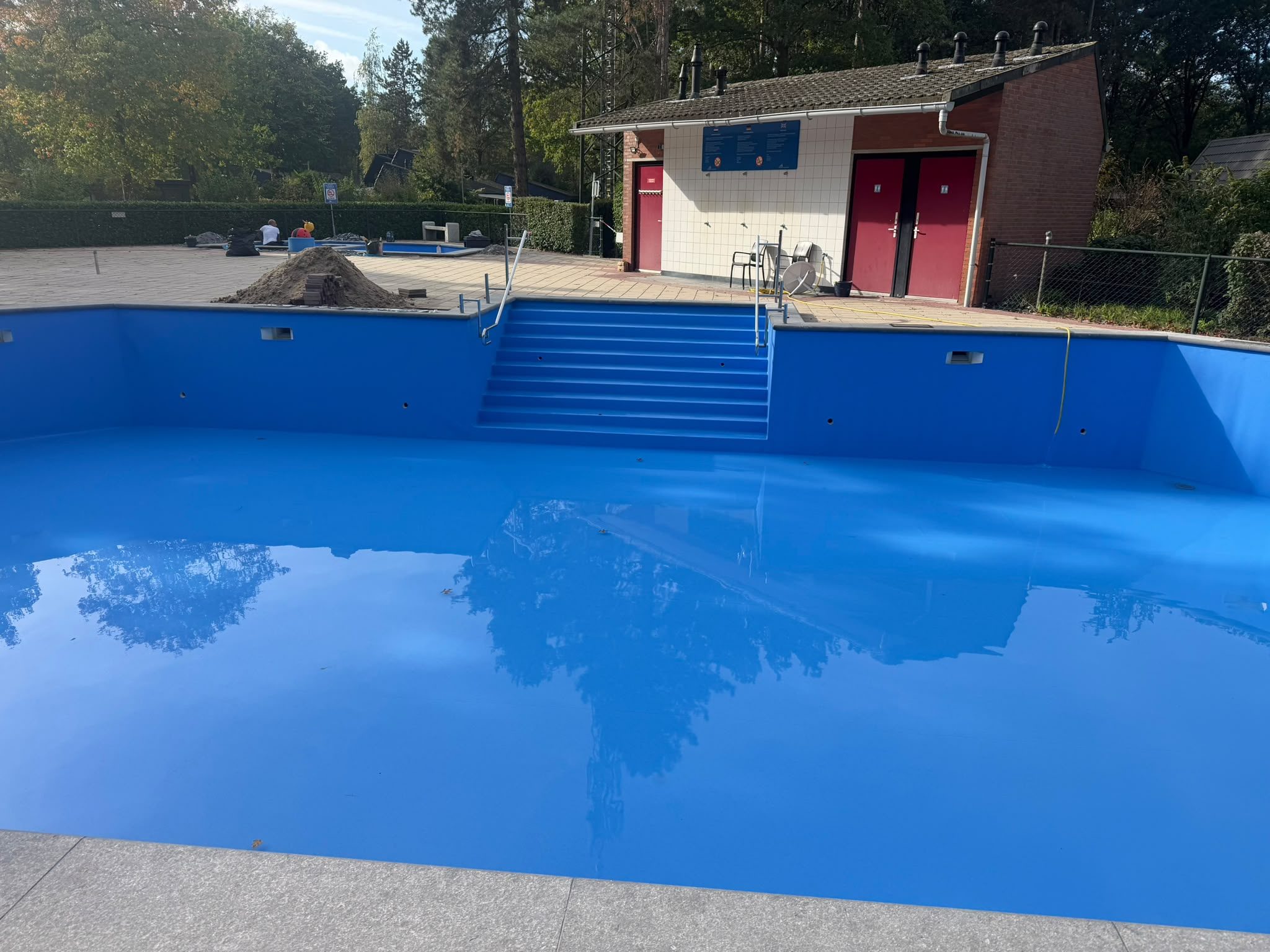 Brede zwembadtrap met leuningen en blauwe binnenzijde van het grote buitenbad. · foto 4