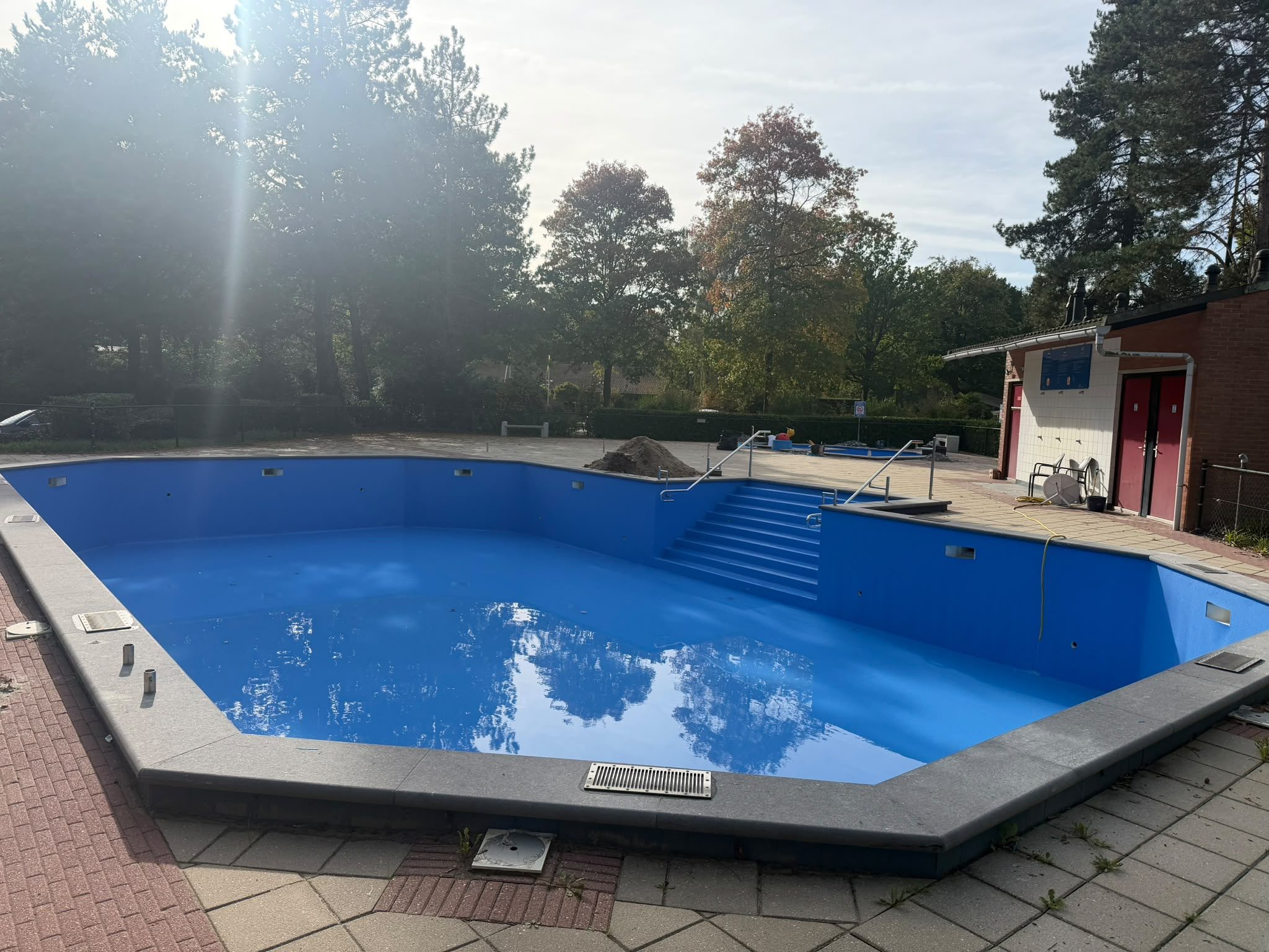 Overzicht van het grote blauwe buitenbad en de bestrating rondom. · foto 5