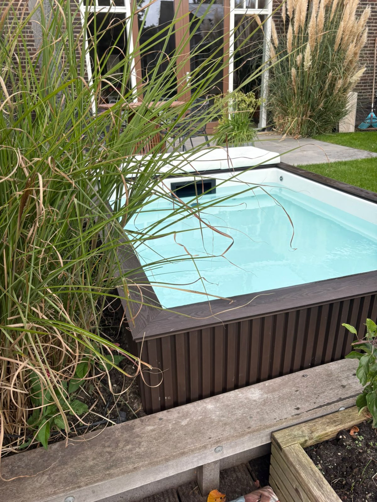 Zicht op het water van de minipool langs de hoge beplanting. · foto 6