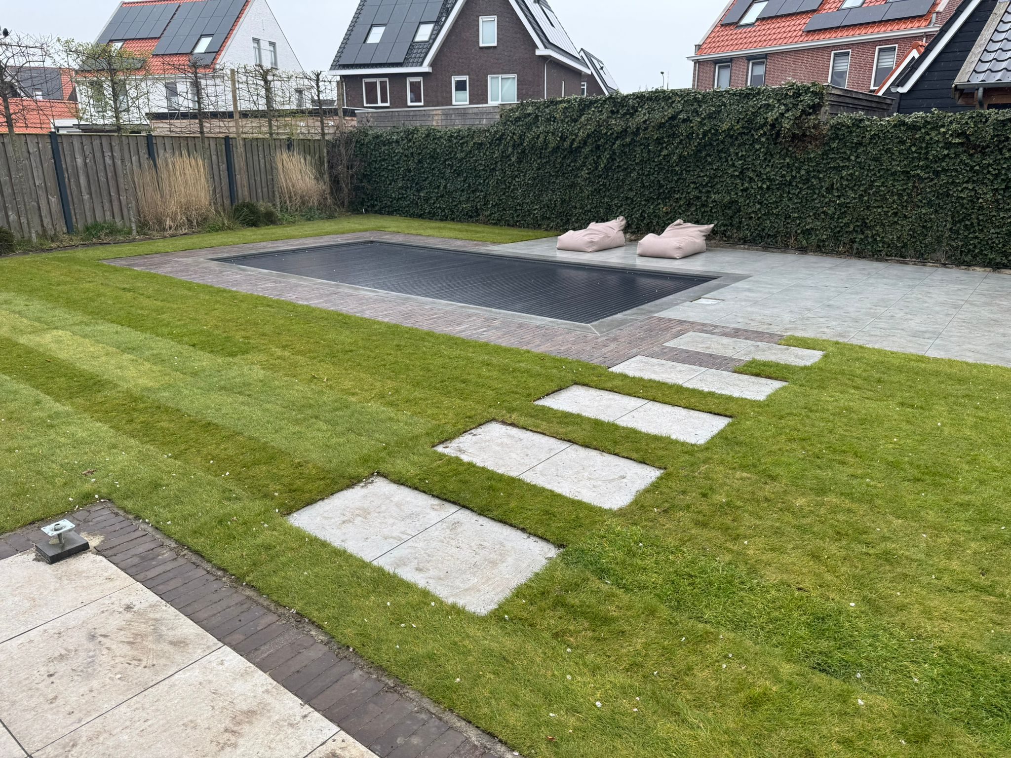 Afgedekt zwembad met terras, gazon en staptegels in Middelburg.
