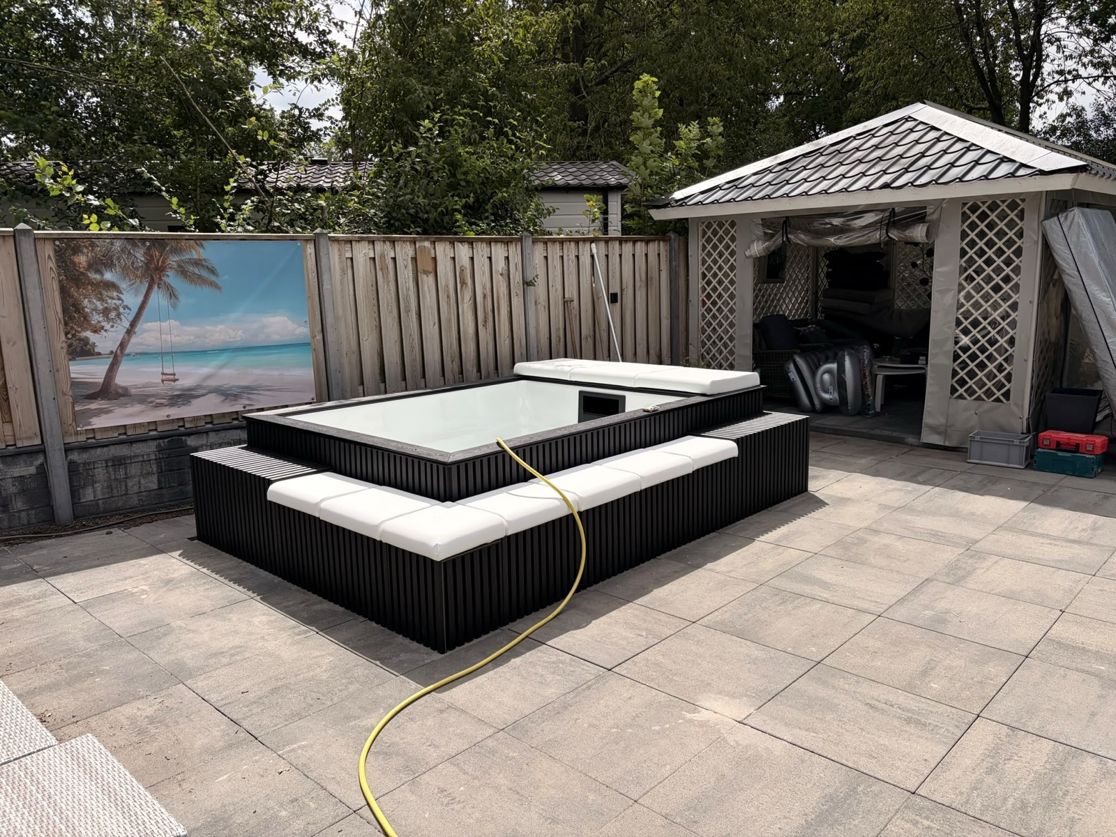 Minipool PRO in Biddinghuizen met zwarte buitenbekleding en witte zitkussens op een terras.
