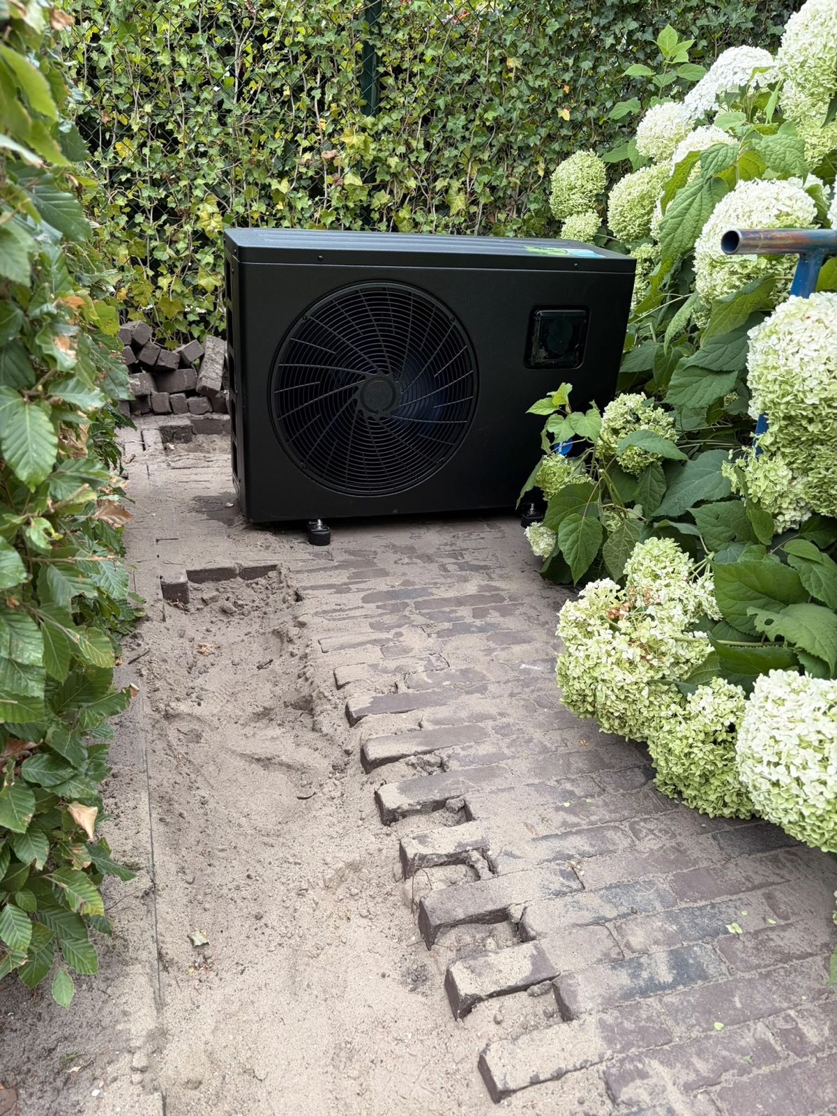 Warmtepomp naast de minipool tussen de beplanting in Ossendrecht.
