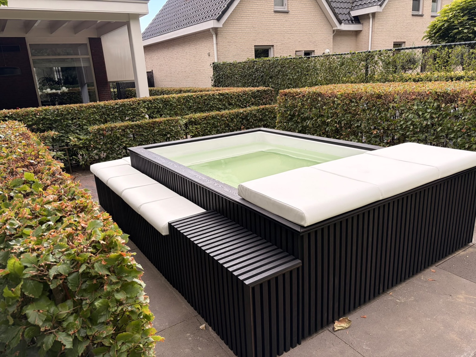 Minipool in Ossendrecht met witte binnenzijde en zitkussens rondom.