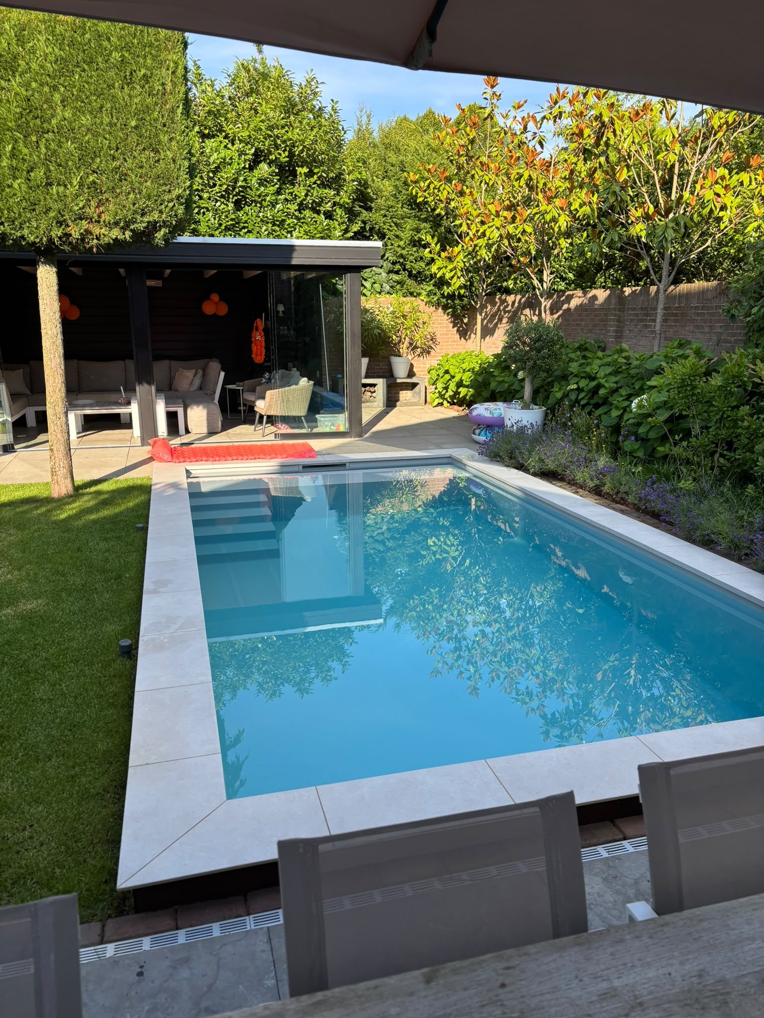 Zwembad met brede instap en poolhouse in een groene tuin in Oss bij daglicht. · foto 2