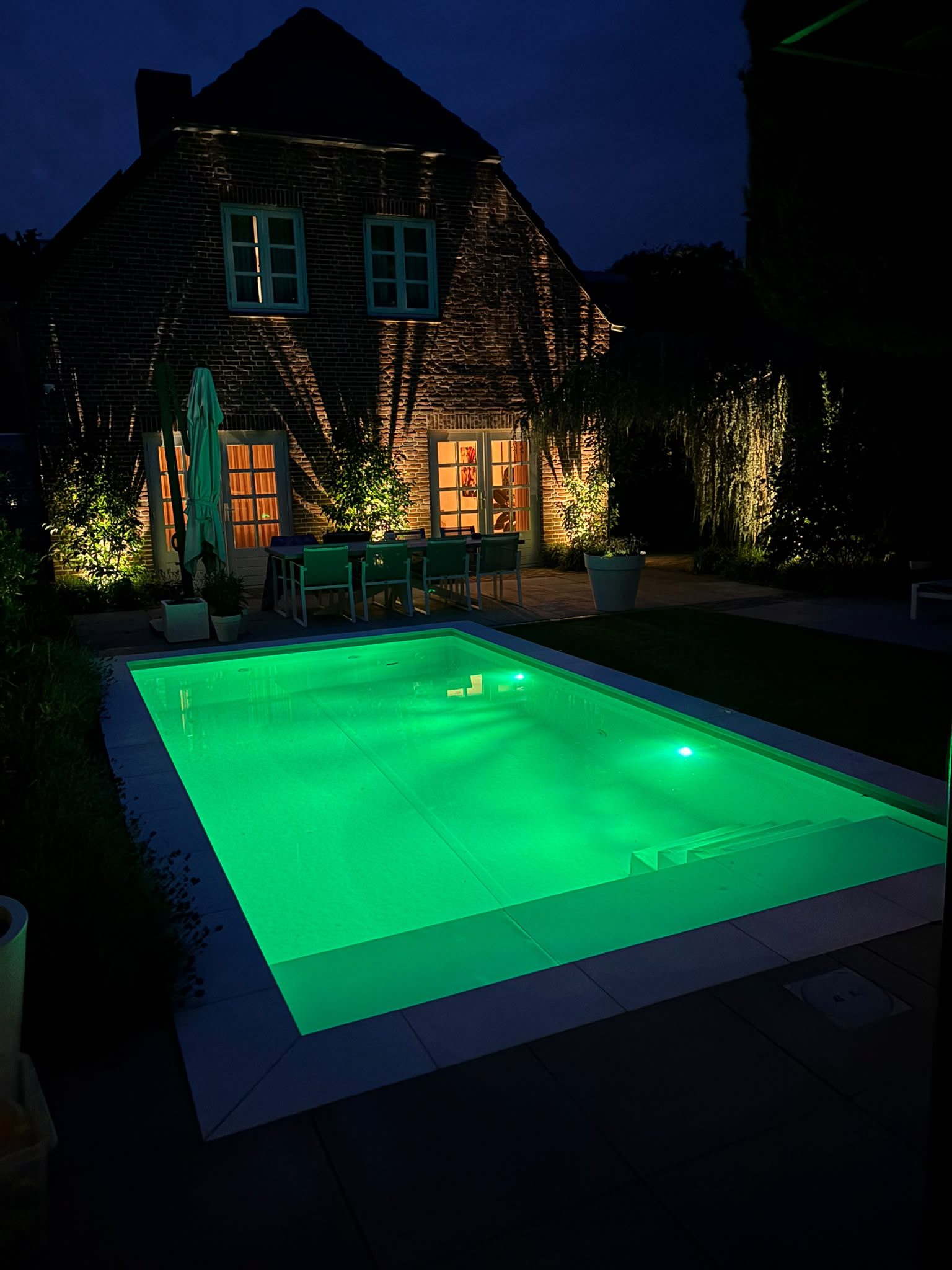 Zwembad met groene verlichting voor de woning in Oss bij avond. · foto 3
